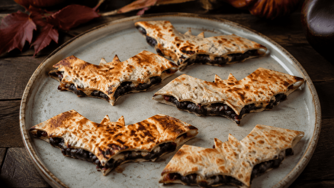 Knusprige dunkle Quesadilla-Stücke in Fledermausform mit Käsefüllung